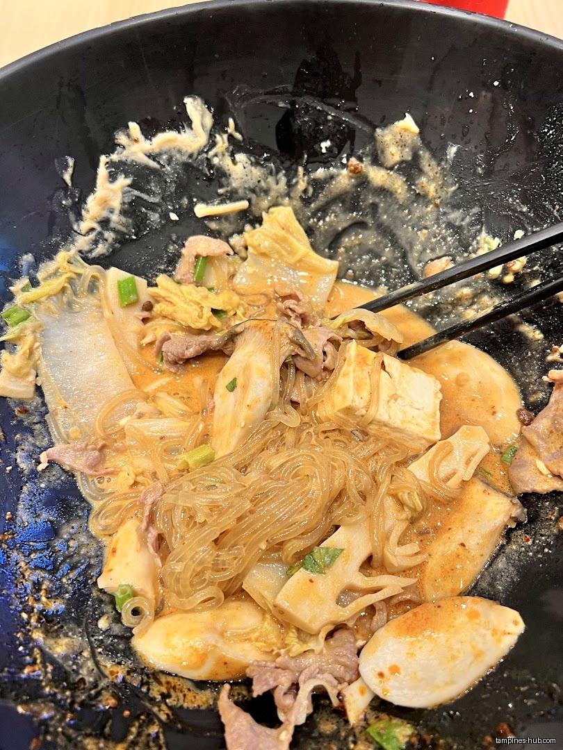 A bowl of Mala Tang with noodles, tofu, meat, and vegetables.