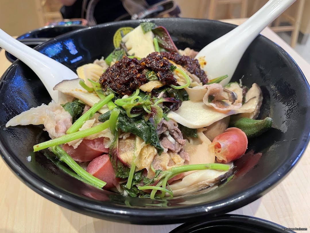 A bowl of Ma La Tang with various ingredients and two spoons.