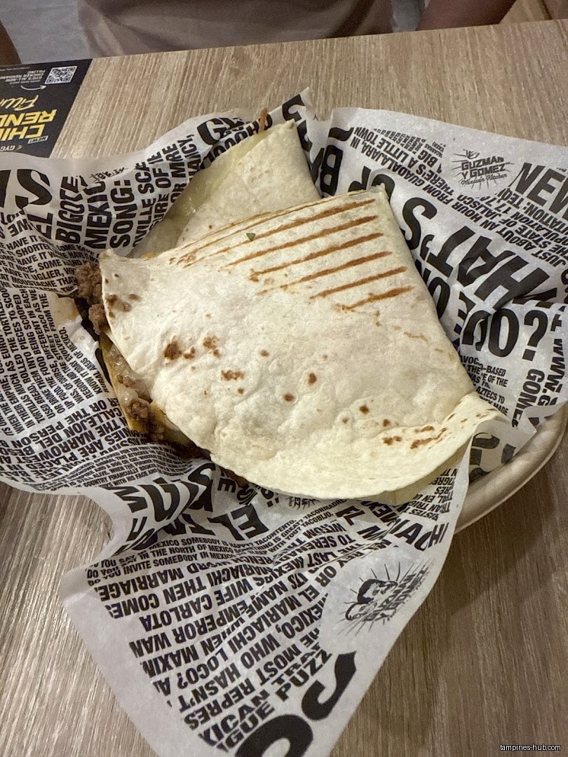 A Guzman y Gomez quesadilla sits in a branded paper-lined basket.