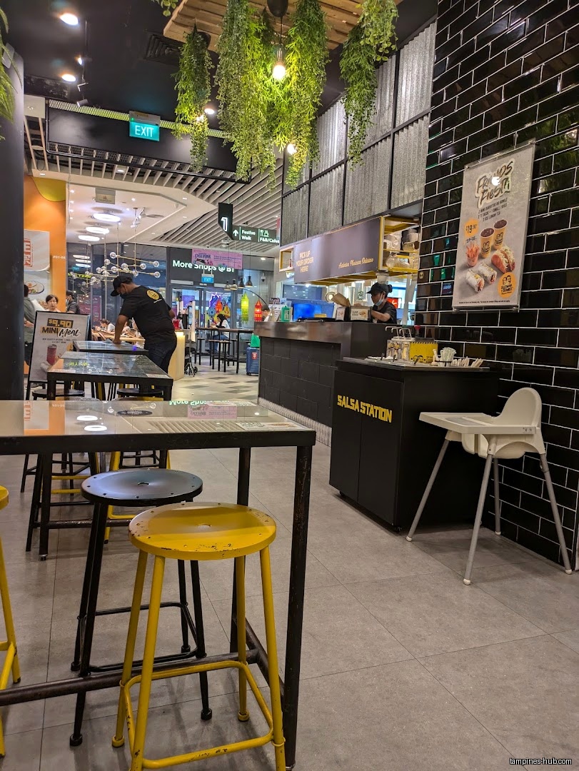 Interior view of Guzman y Gomez with tables, stools, and salsa station.