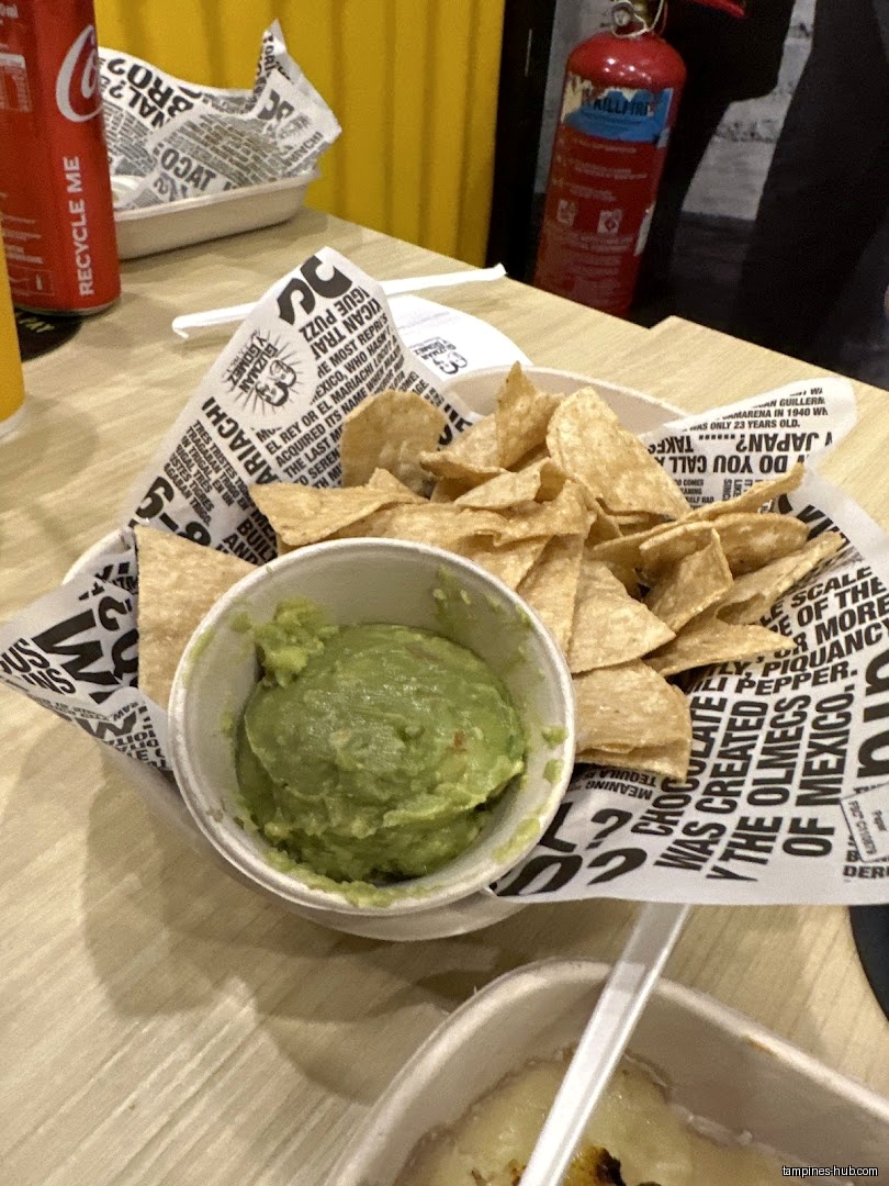 Chips and guacamole are served in a paper-lined bowl at Guzman y Gomez.