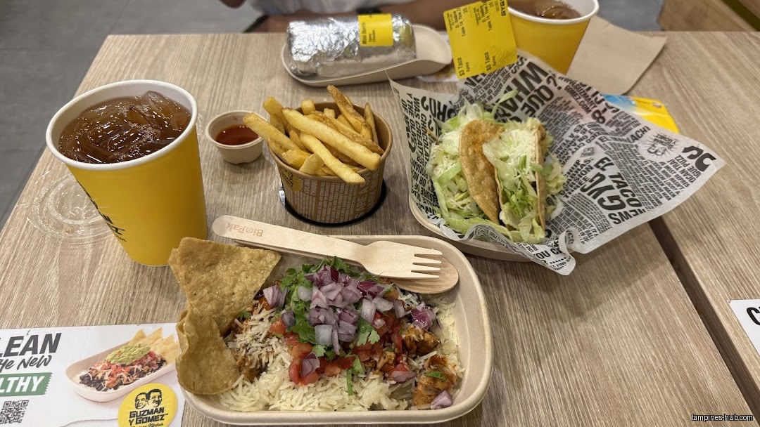 A table with Guzman y Gomez food including tacos, fries, and a burrito.