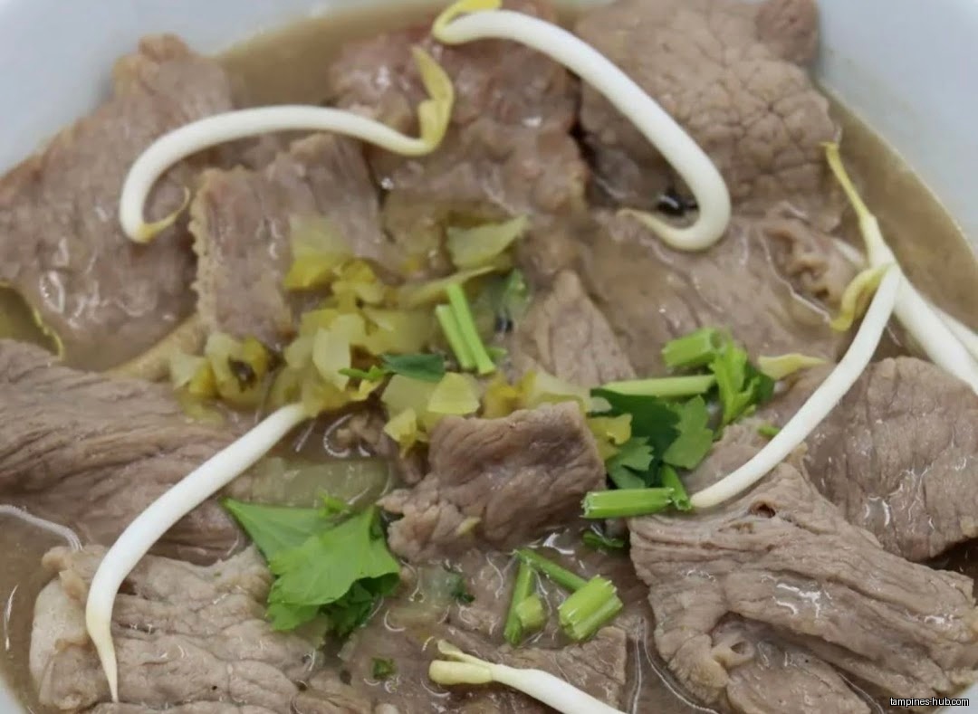 Close-up of Hainan beef noodle soup with sprouts and cilantro.