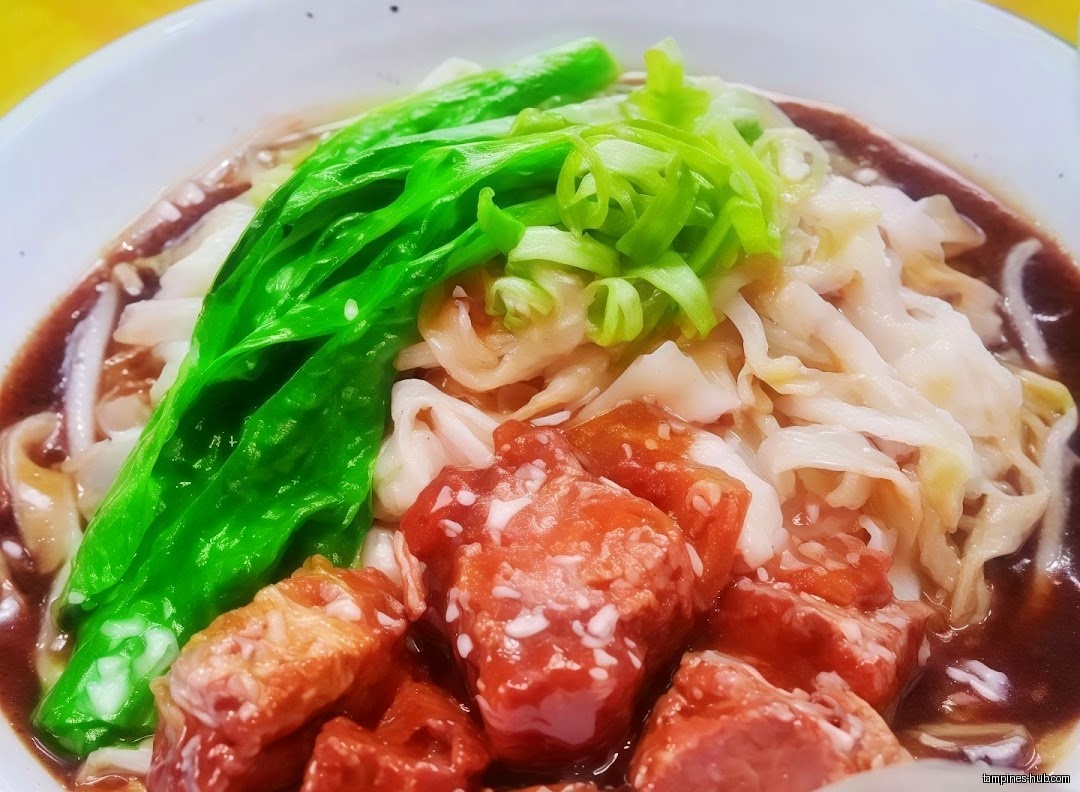 A bowl of Hainan beef noodle with vegetables and sauce.