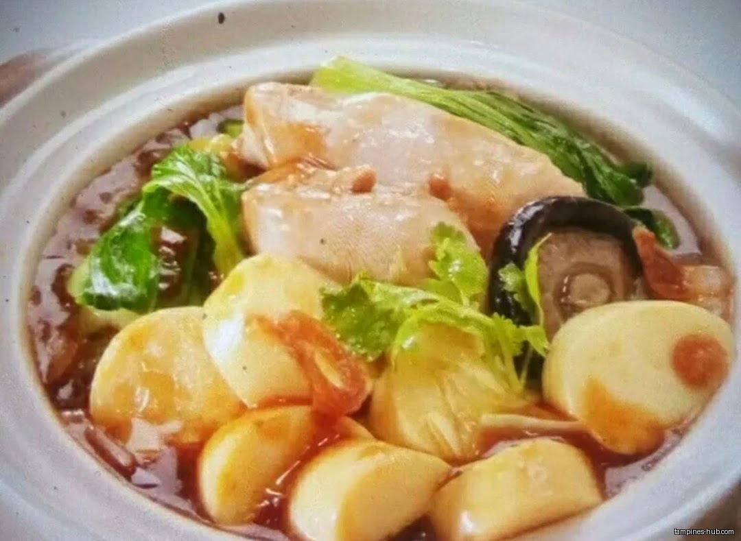 A close-up of a claypot dish with tofu, fish, and vegetables.