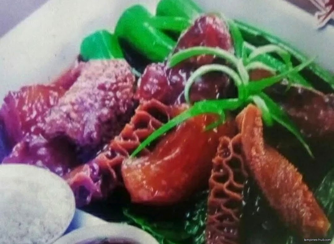 Close-up of a dish with tripe, greens, and sauce.