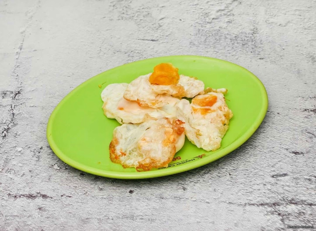 A green plate holds fried eggs with a dollop of orange topping.