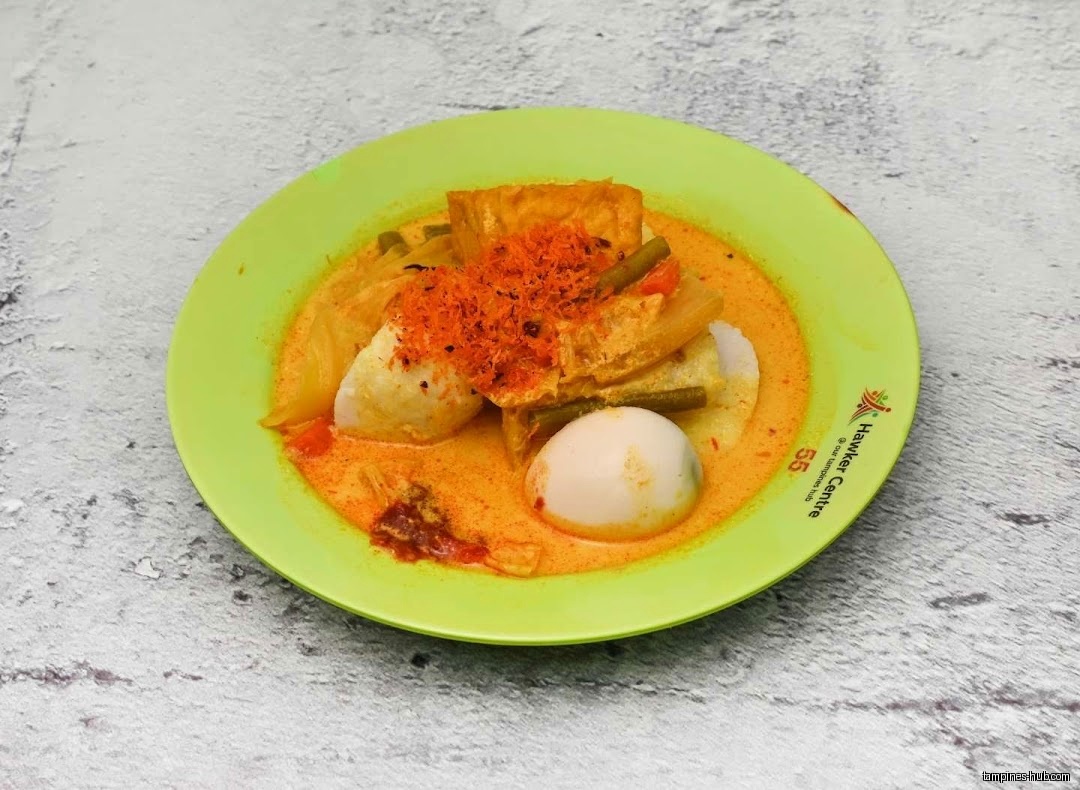 A plate of Lontong Sayur with egg, tofu, and vegetables in curry.