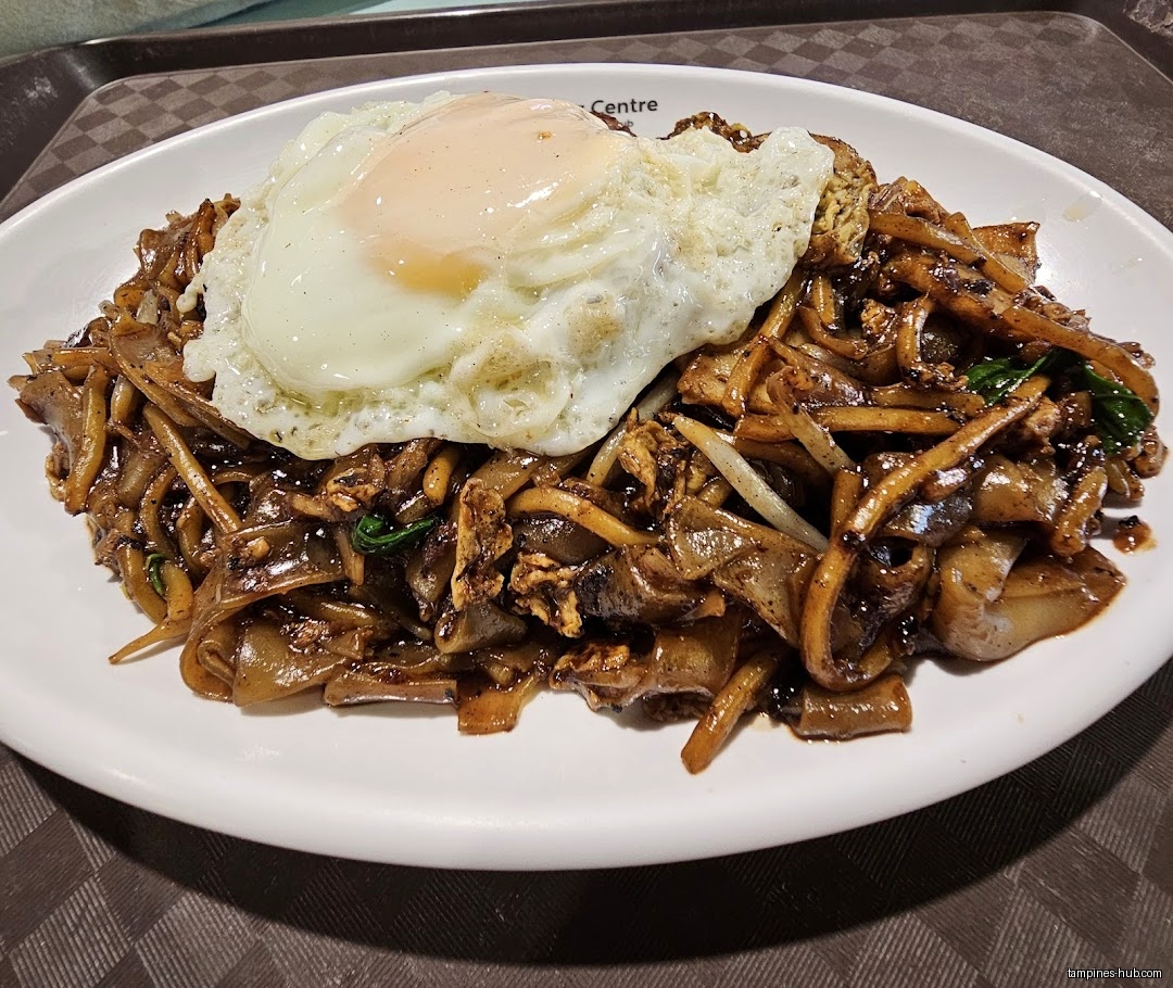 A plate of Char Kway Teow with a fried egg on top.
