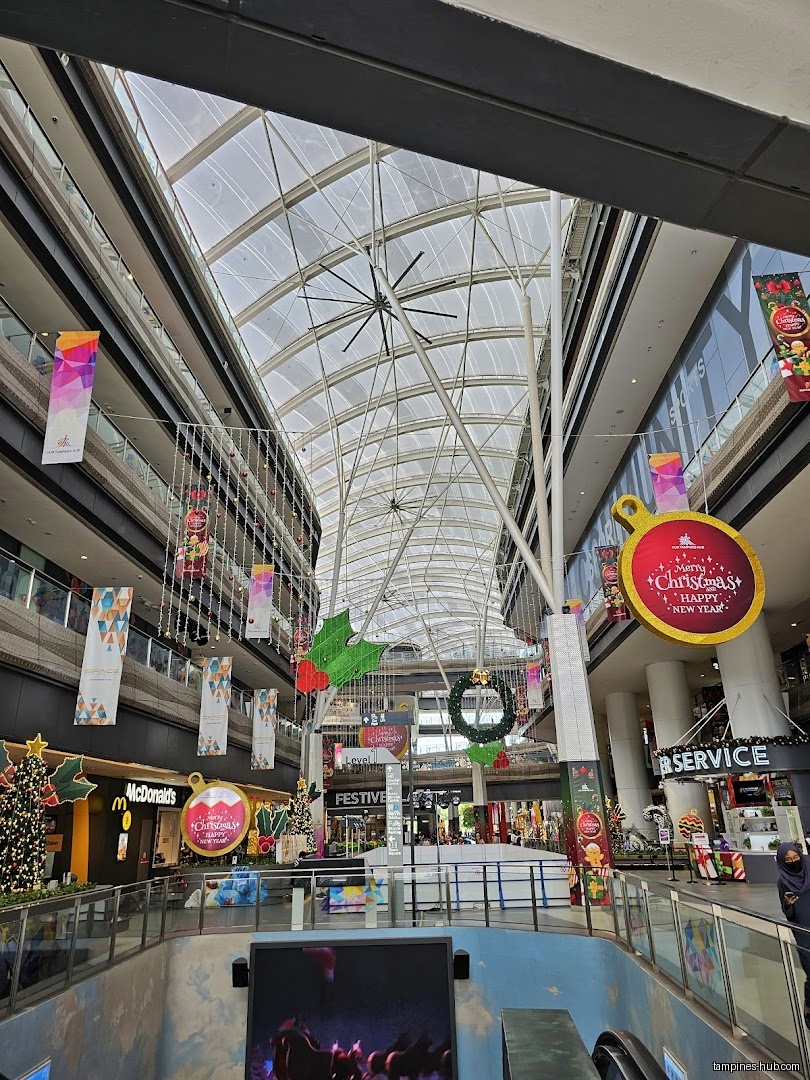 Interior view of Our Tampines Hub with Christmas decorations and shops.