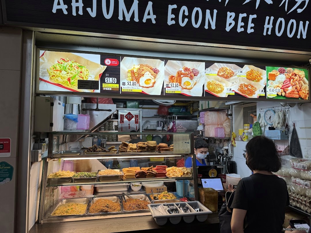 A food stall with a customer and a variety of dishes displayed.