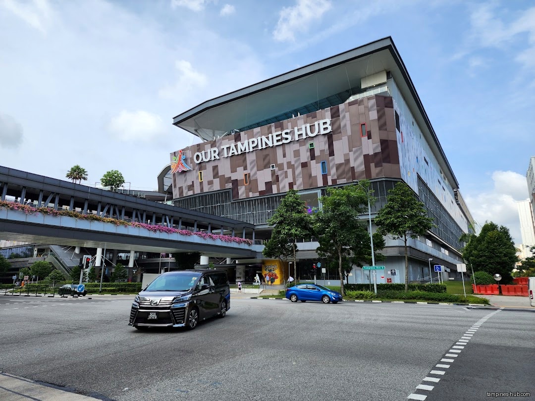 Exterior view of Our Tampines Hub building with cars on the road.