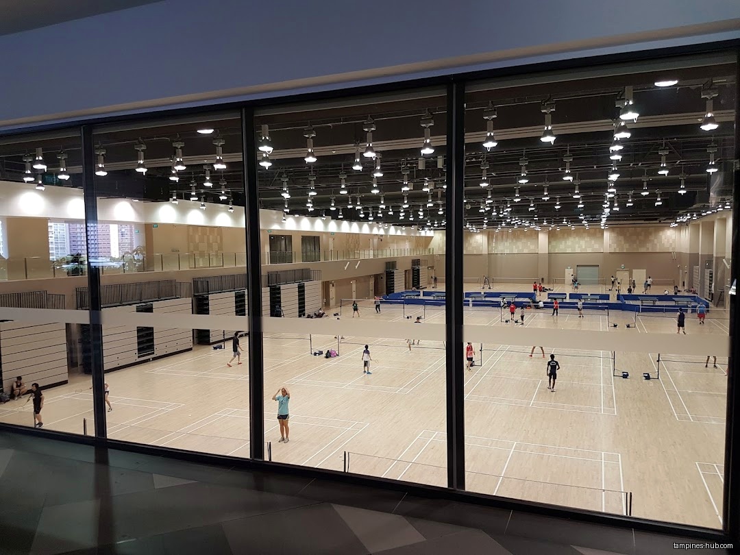 A large indoor badminton court with multiple games in progress.