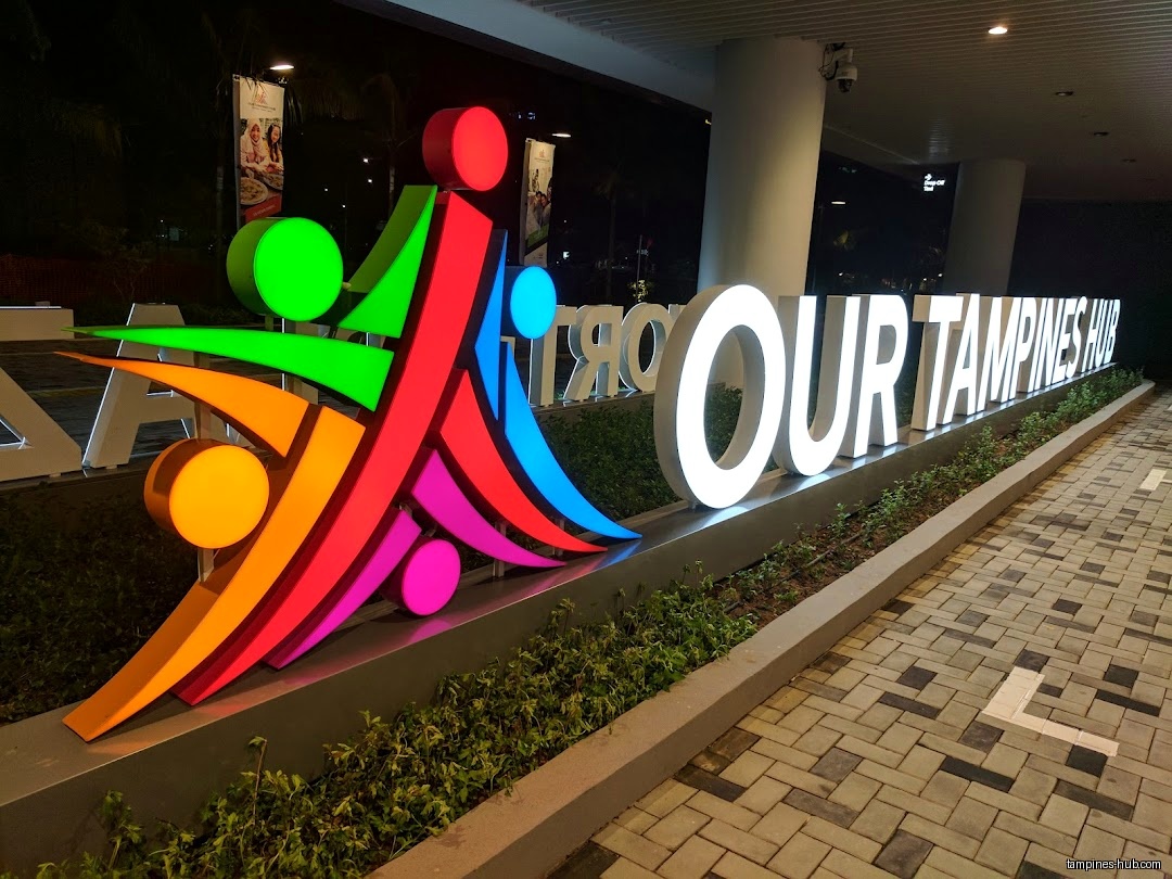 Illuminated sign for 'Our Tampines Hub' with a colorful abstract logo.