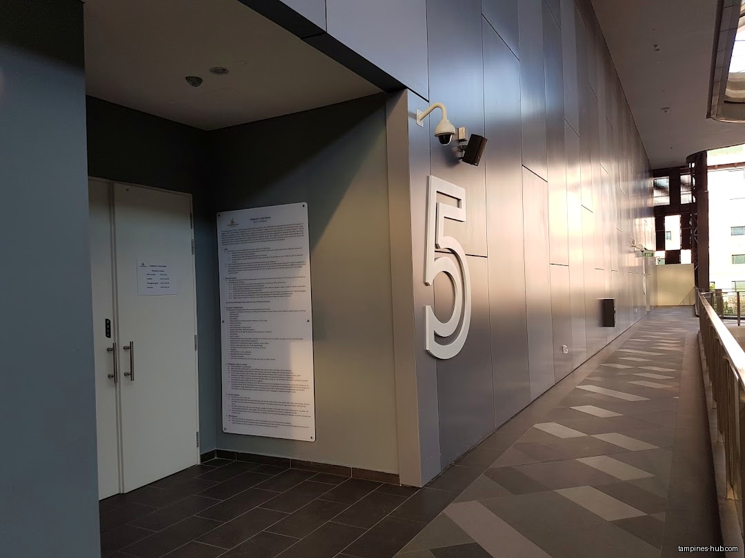 Exterior hallway with a door, sign, number 5, and security cameras.