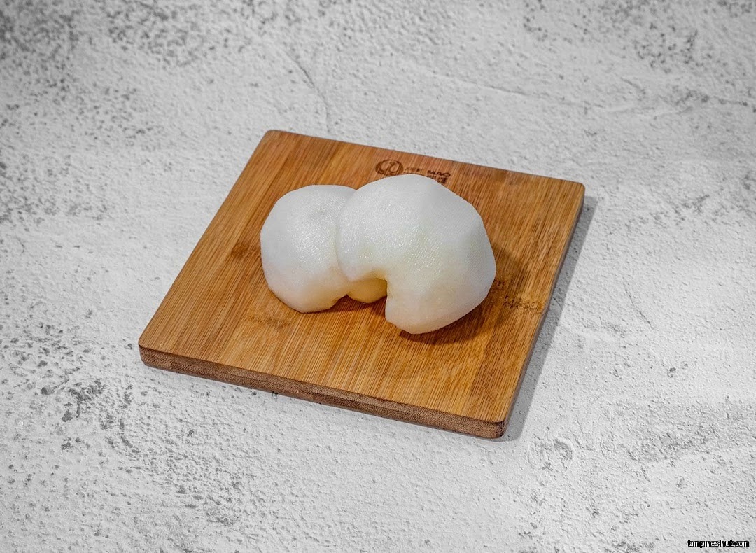 Two peeled pear halves sit on a small wooden cutting board.