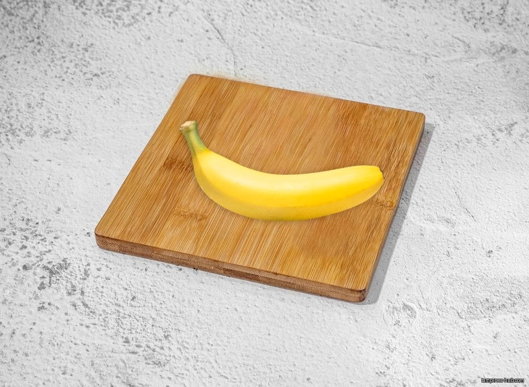 A single banana sits on a small wooden cutting board.