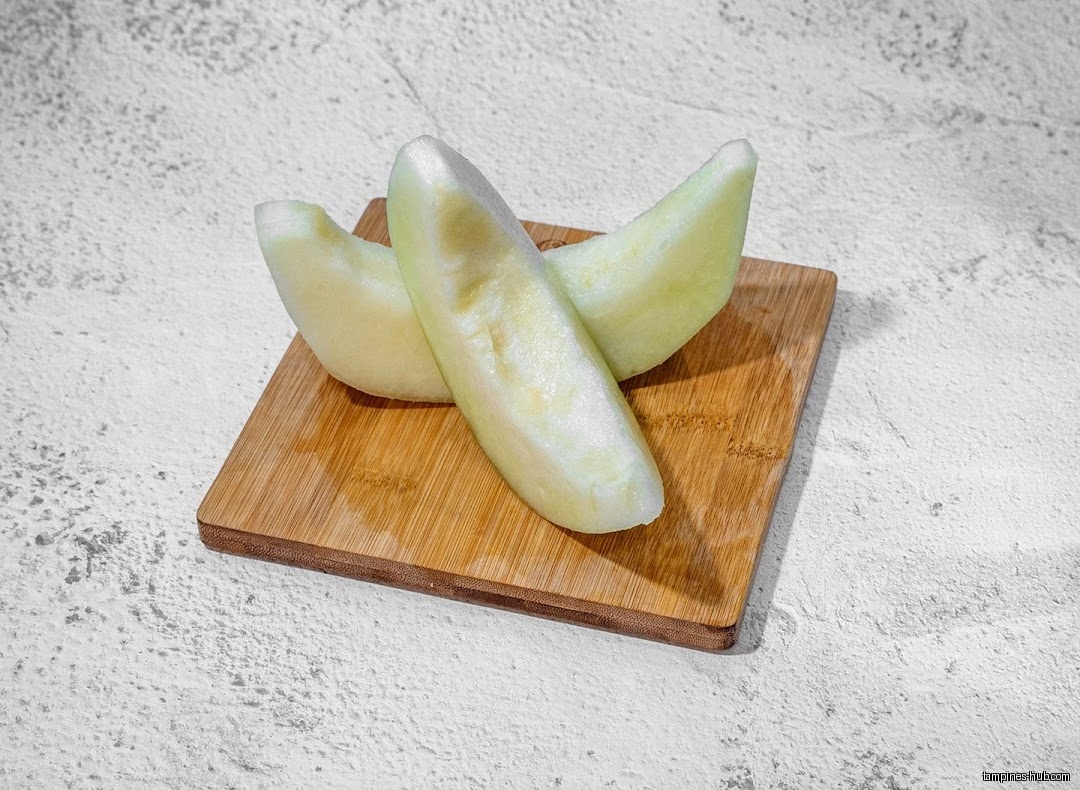 Two slices of honeydew melon on a small wooden cutting board.