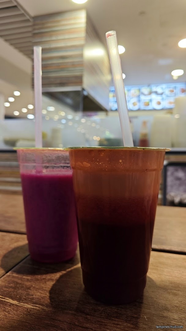Two cups of Holla Juice drinks with straws on a wooden table.