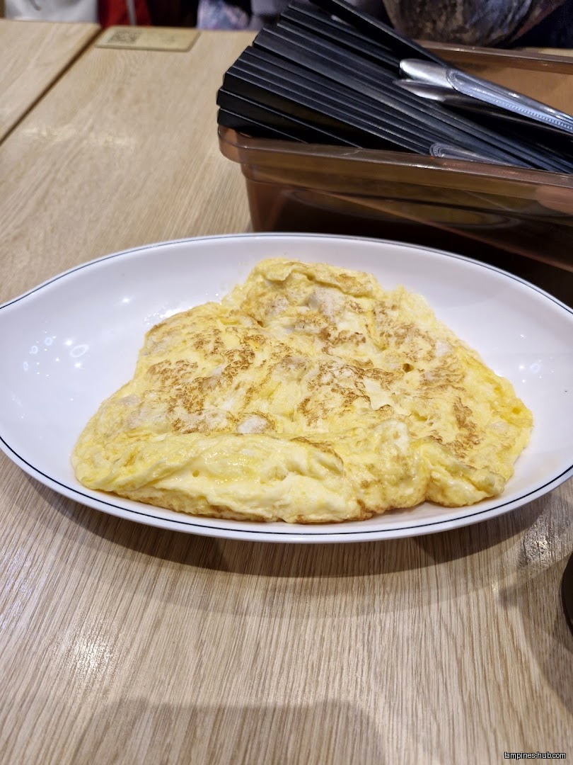 A plate of omelet is on a table with utensils.
