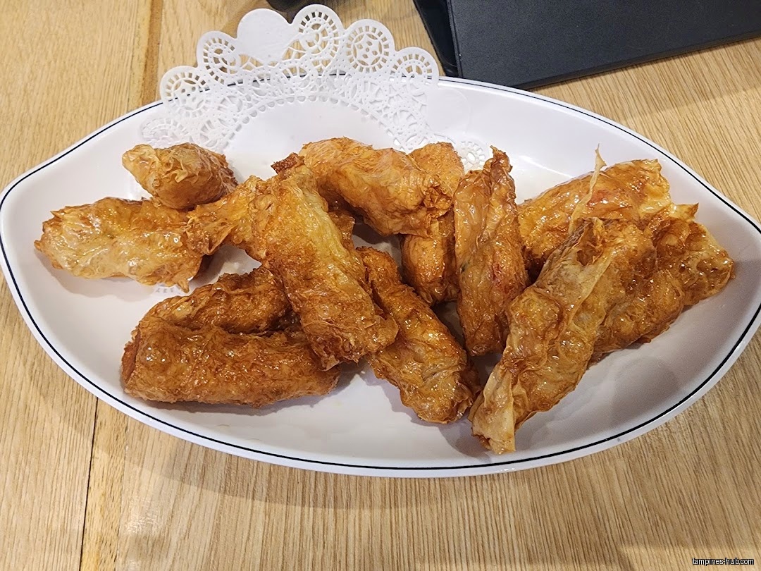 A plate of fried food, possibly bean curd rolls, on a table.