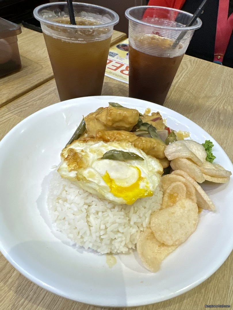 A plate of rice with egg, vegetables, and two drinks on a table.