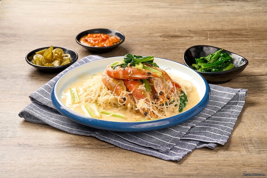 A plate of white bee hoon with prawns and side dishes.