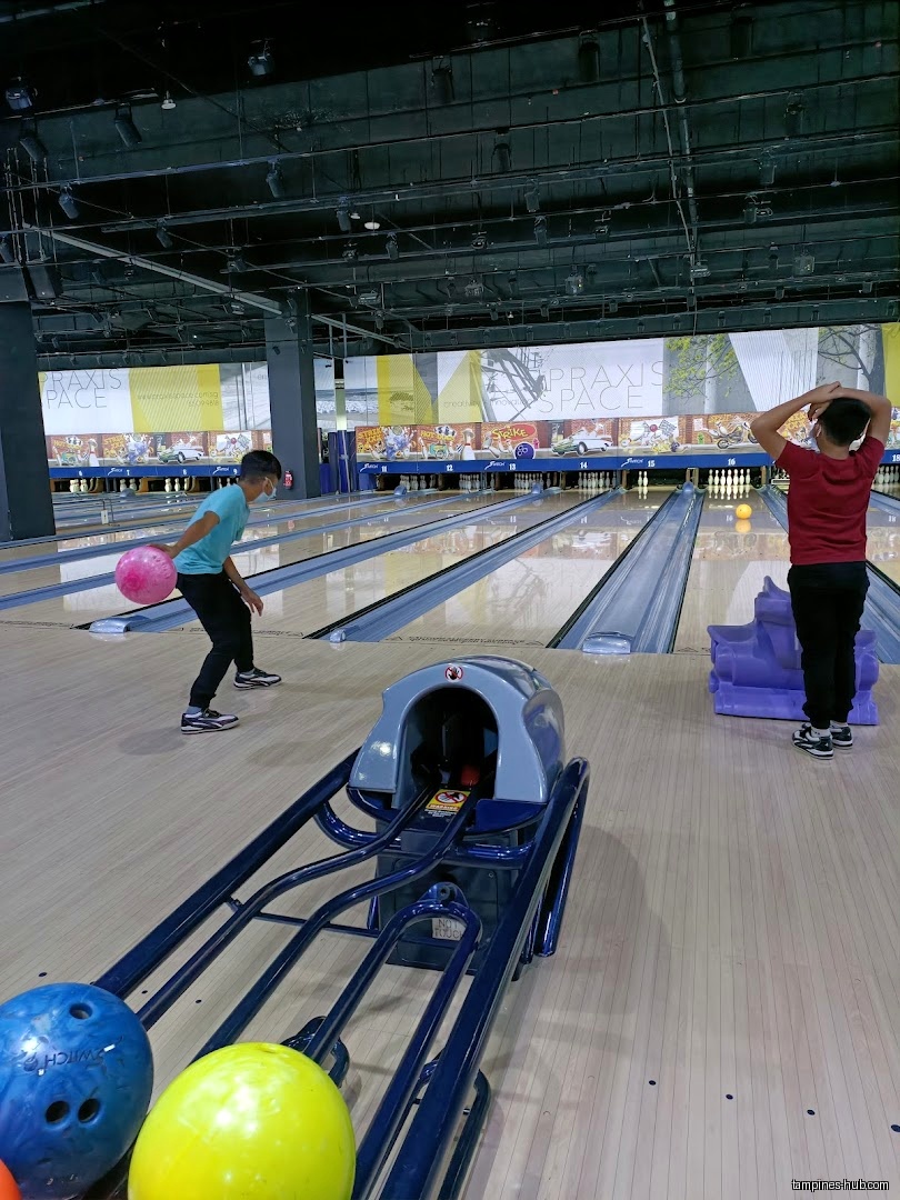 Two people are bowling in a bowling alley with bowling balls.