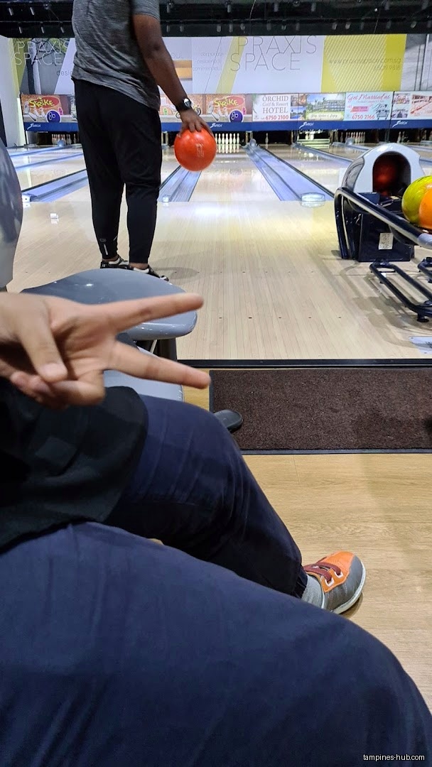 A person is bowling with an orange ball at a bowling alley.