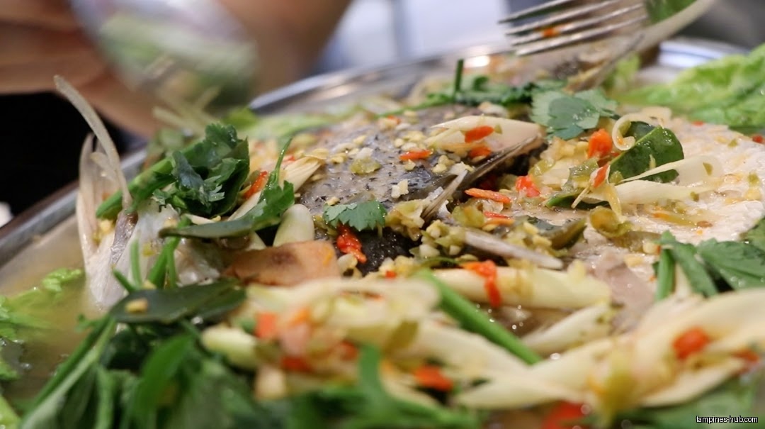 Close-up of a steamed fish dish with herbs and spices.