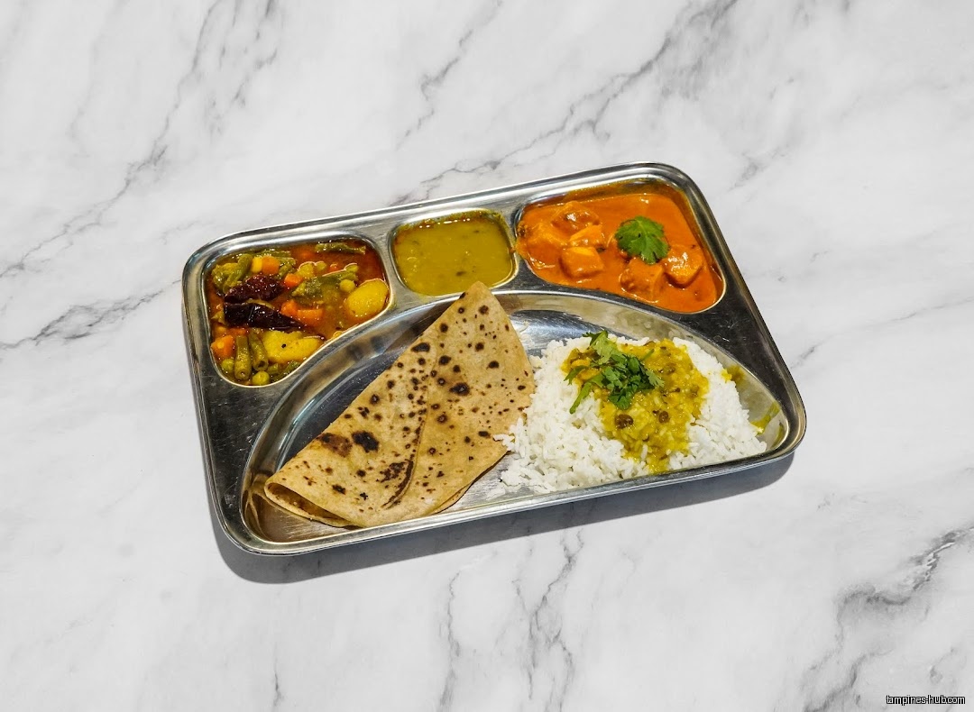 Indian Cuisine's thali meal with rice, roti, vegetables, and curry on a tray.