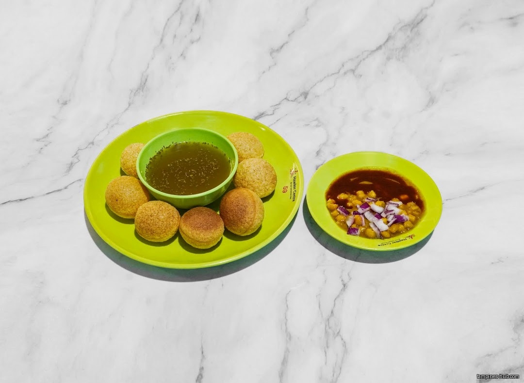 Two green plates with Indian snacks, one with pani puri and the other with chickpeas.