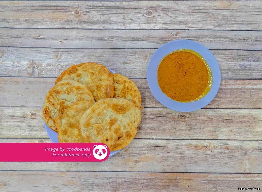 A plate of roti prata and a bowl of curry on a wooden table.