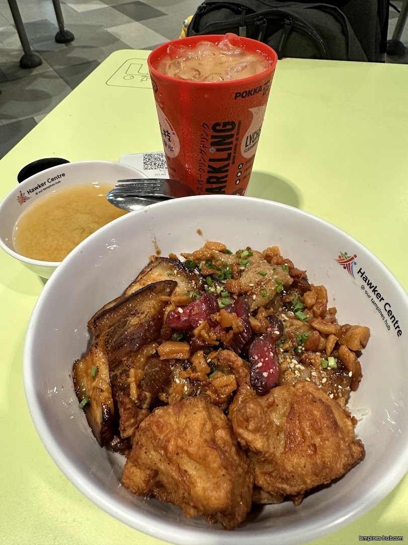 A bowl of food, miso soup, and a Pokka drink on a table.