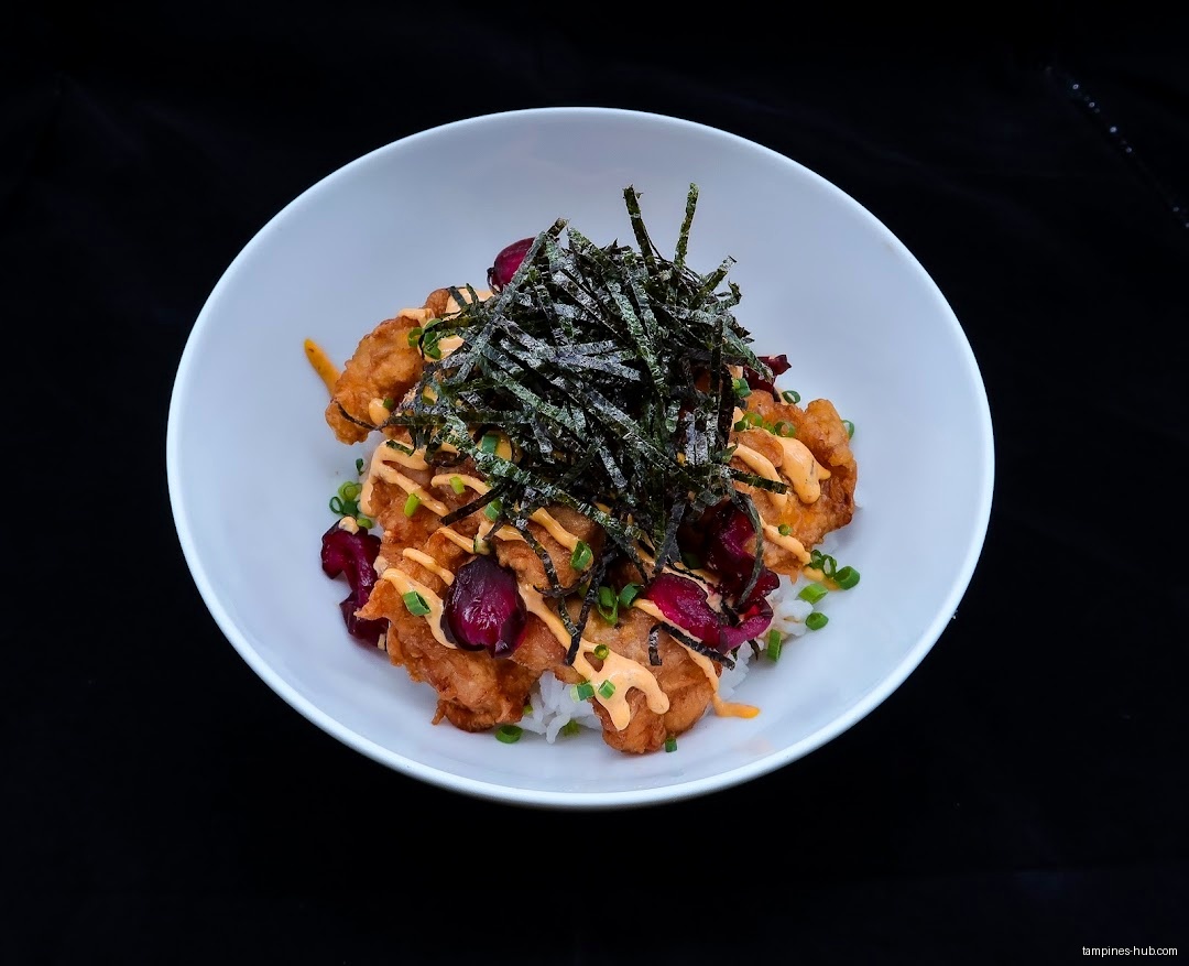 A white bowl filled with fried chicken, seaweed, and sauce.