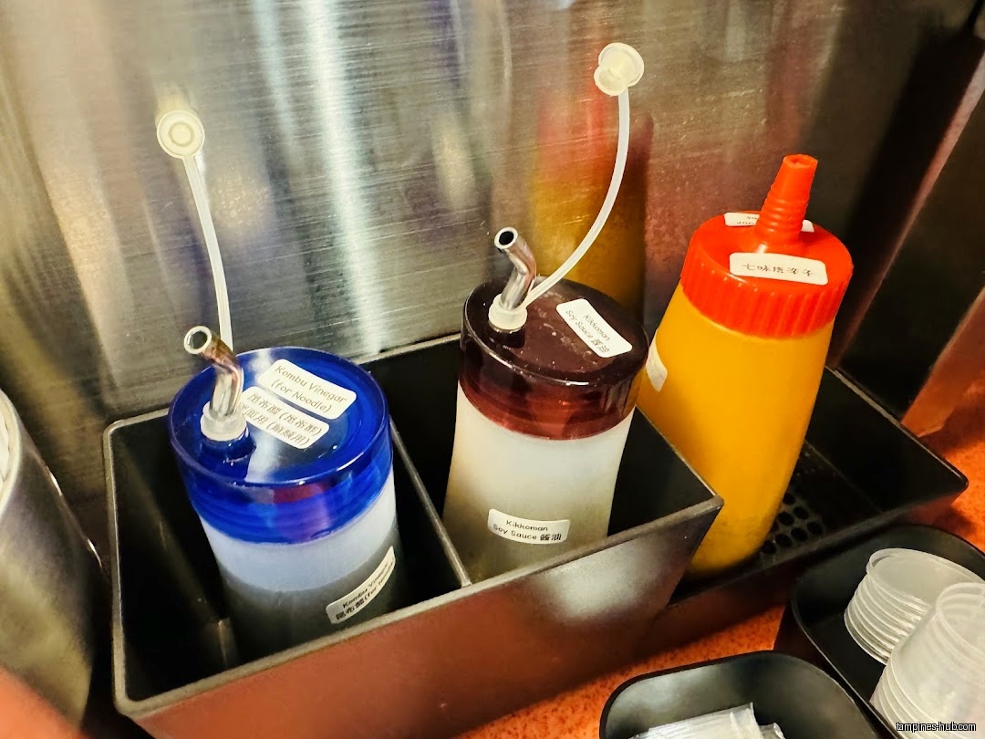 The image shows condiment bottles, including soy sauce and vinegar, in a container.