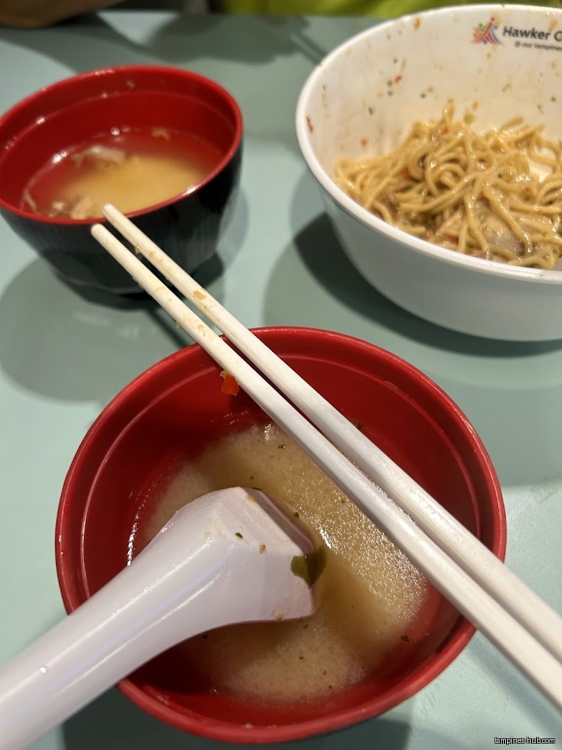 Bowls of food, including noodles and soup, with chopsticks and a spoon.