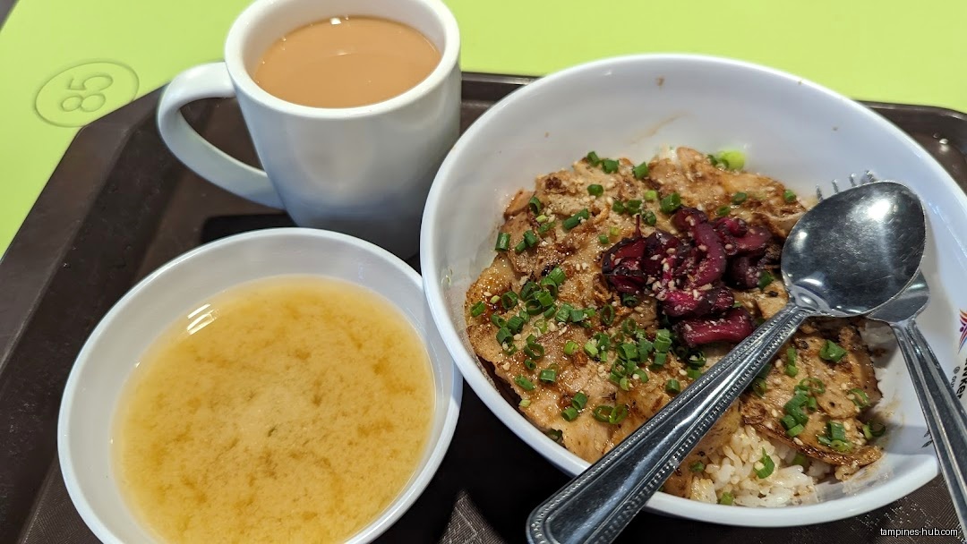 A bowl of rice with meat, soup, and a cup of tea on a tray.