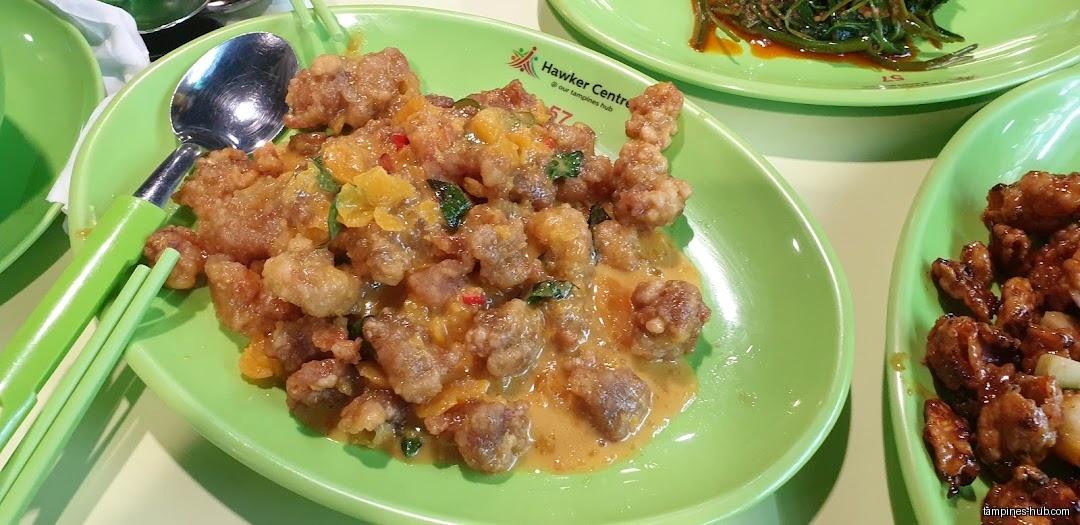 A plate of fried meat with sauce and other dishes on green plates.