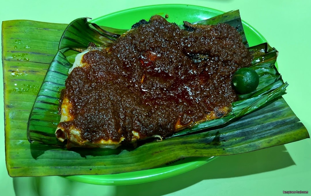 BBQ seafood dish with dark sauce on banana leaf and green plate.