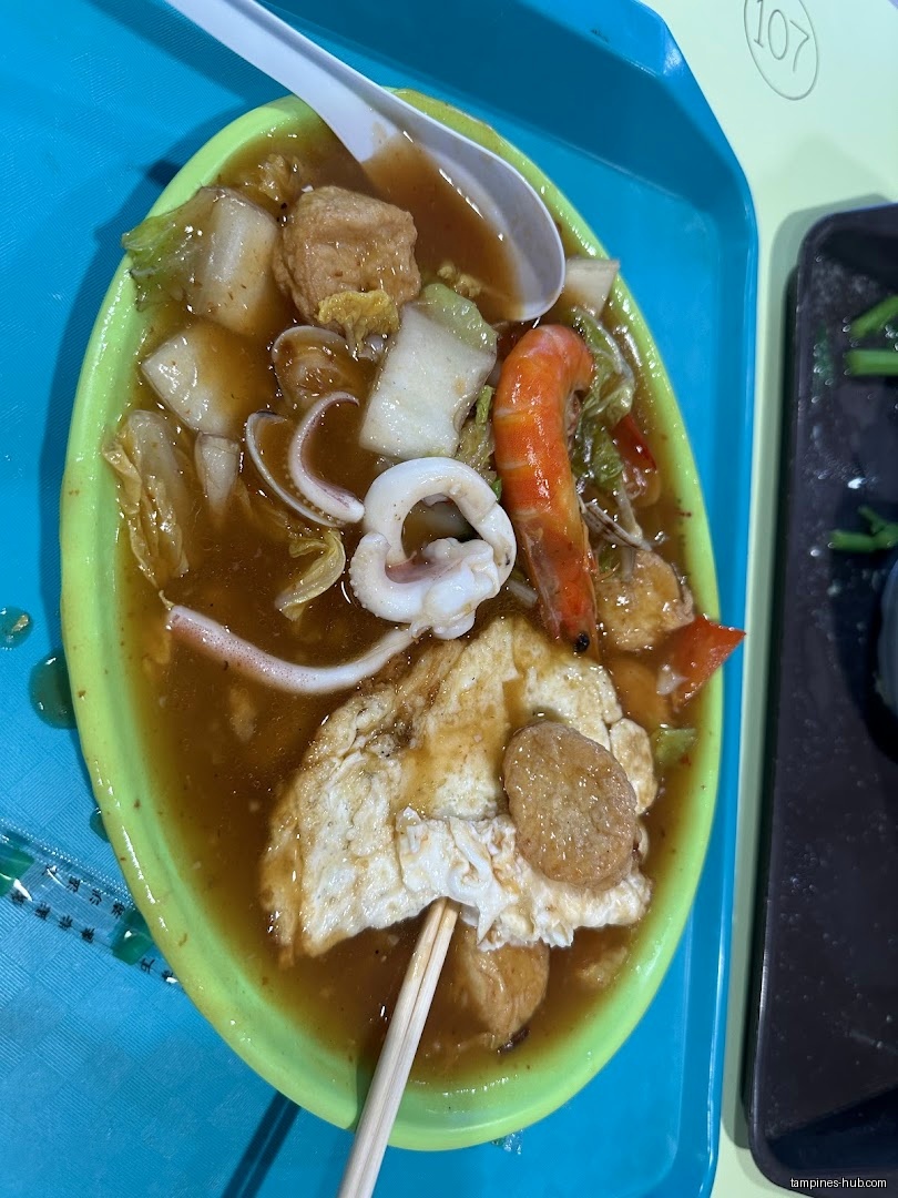 A plate of food with seafood, tofu, and vegetables in sauce.