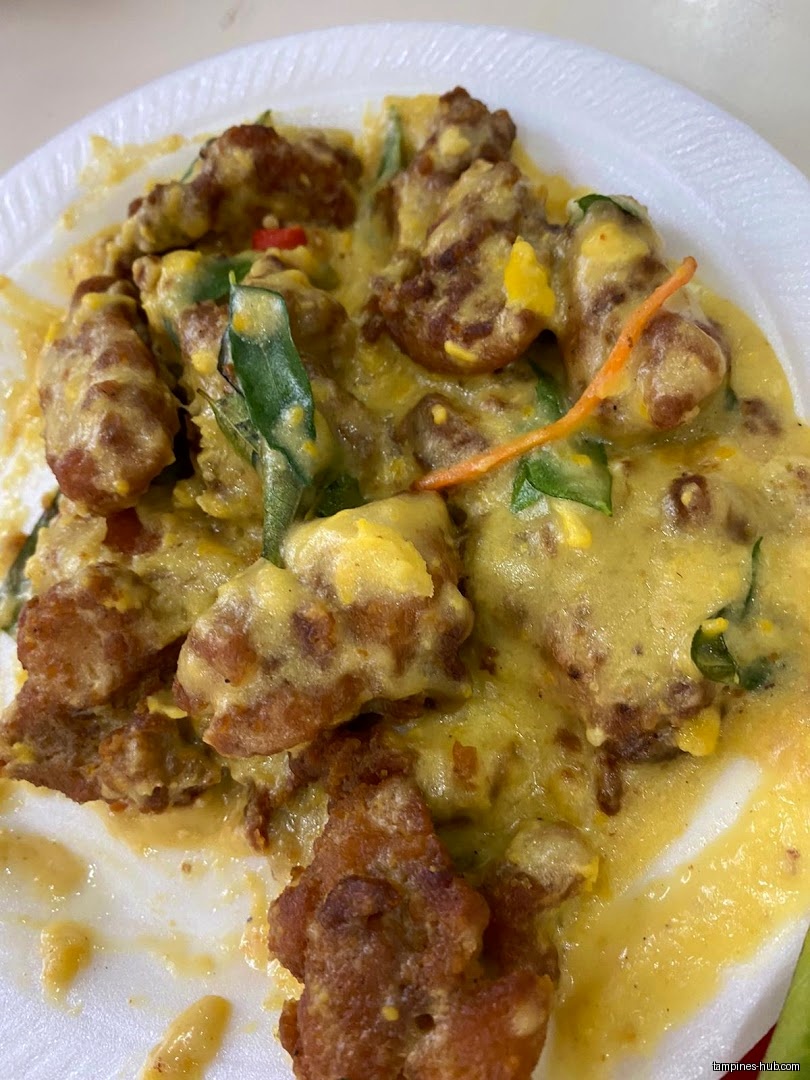 A plate of fried food covered in a yellow sauce with vegetables.