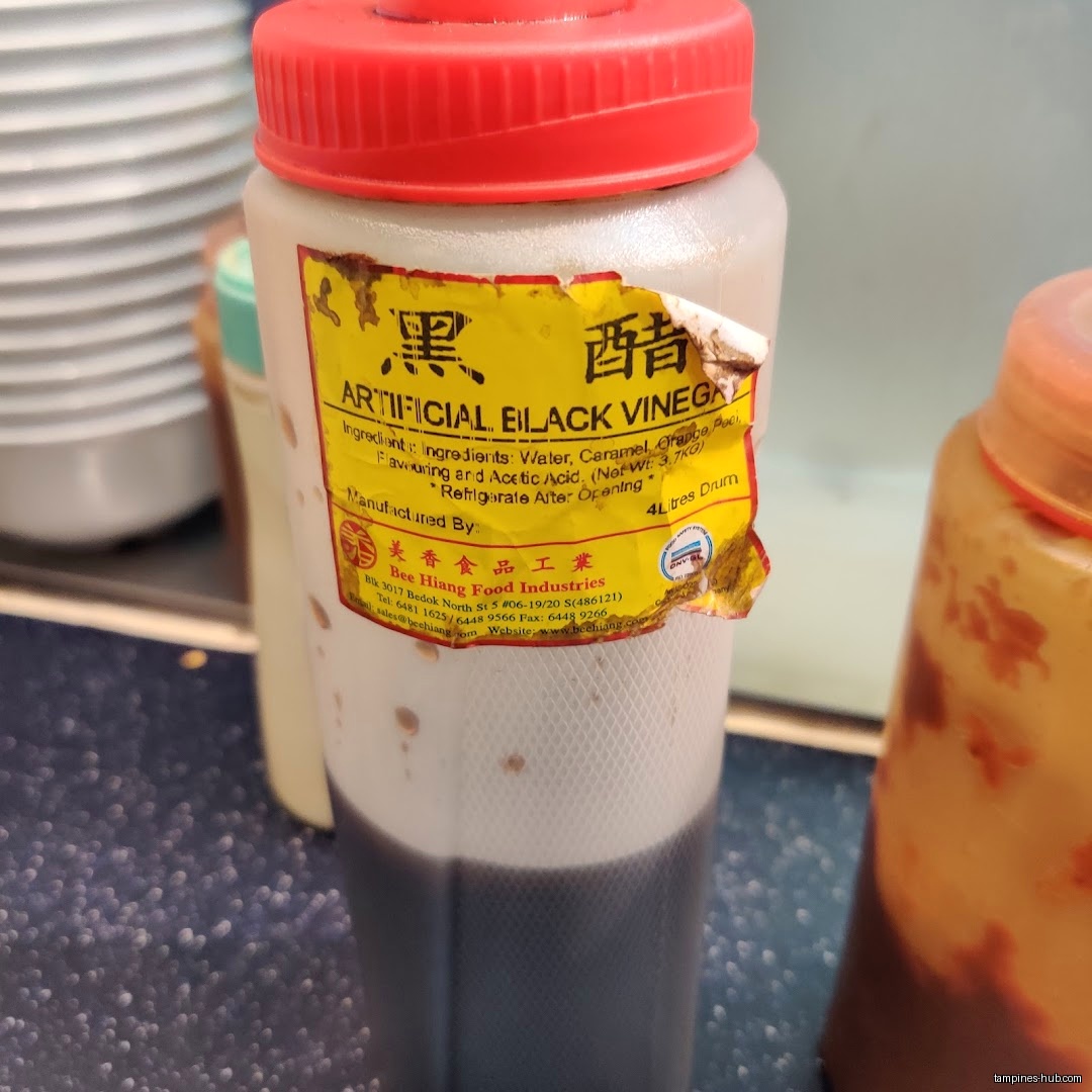 A bottle of artificial black vinegar with a red lid is shown.