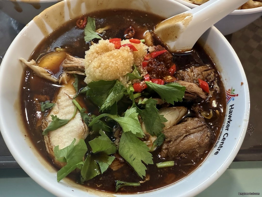 A bowl of Lor Mee with dark gravy, meat, and toppings.