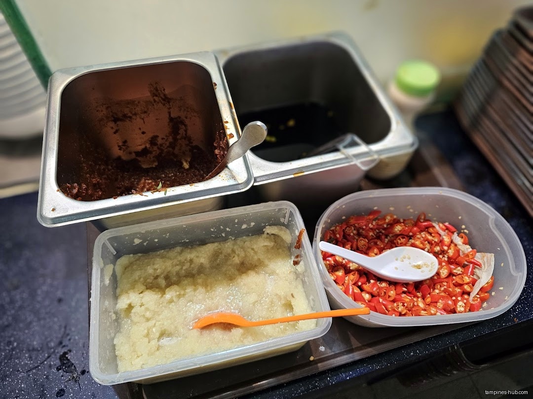 Close-up of condiments: chili, garlic, and dark sauces in containers.