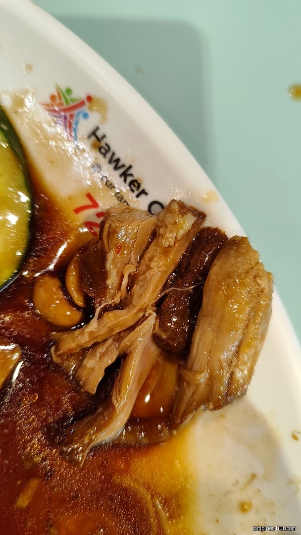 Close-up of braised meat and sauce on a plate with a logo.