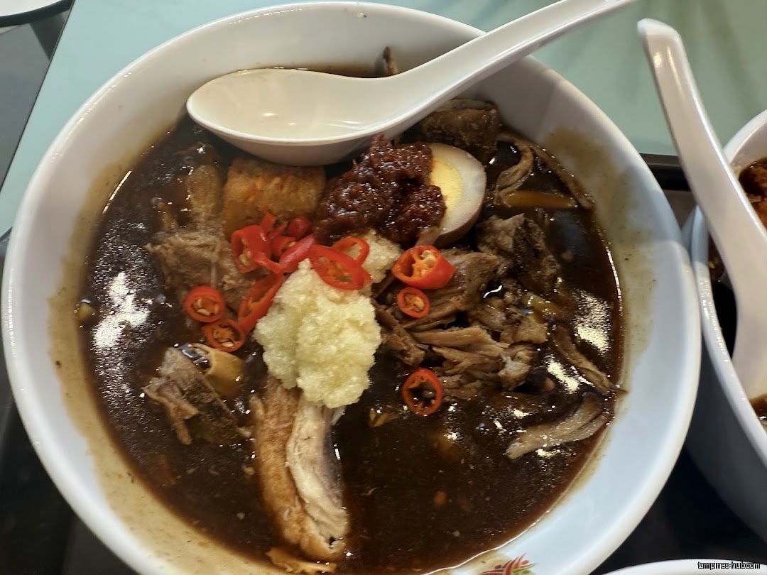 A bowl of Lor Mee with various toppings and a spoon.