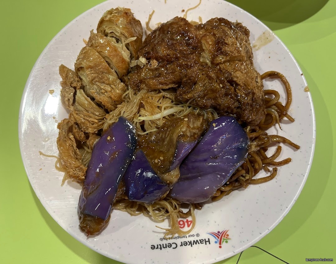 A plate of vegetarian noodles with eggplant and fried tofu is shown.