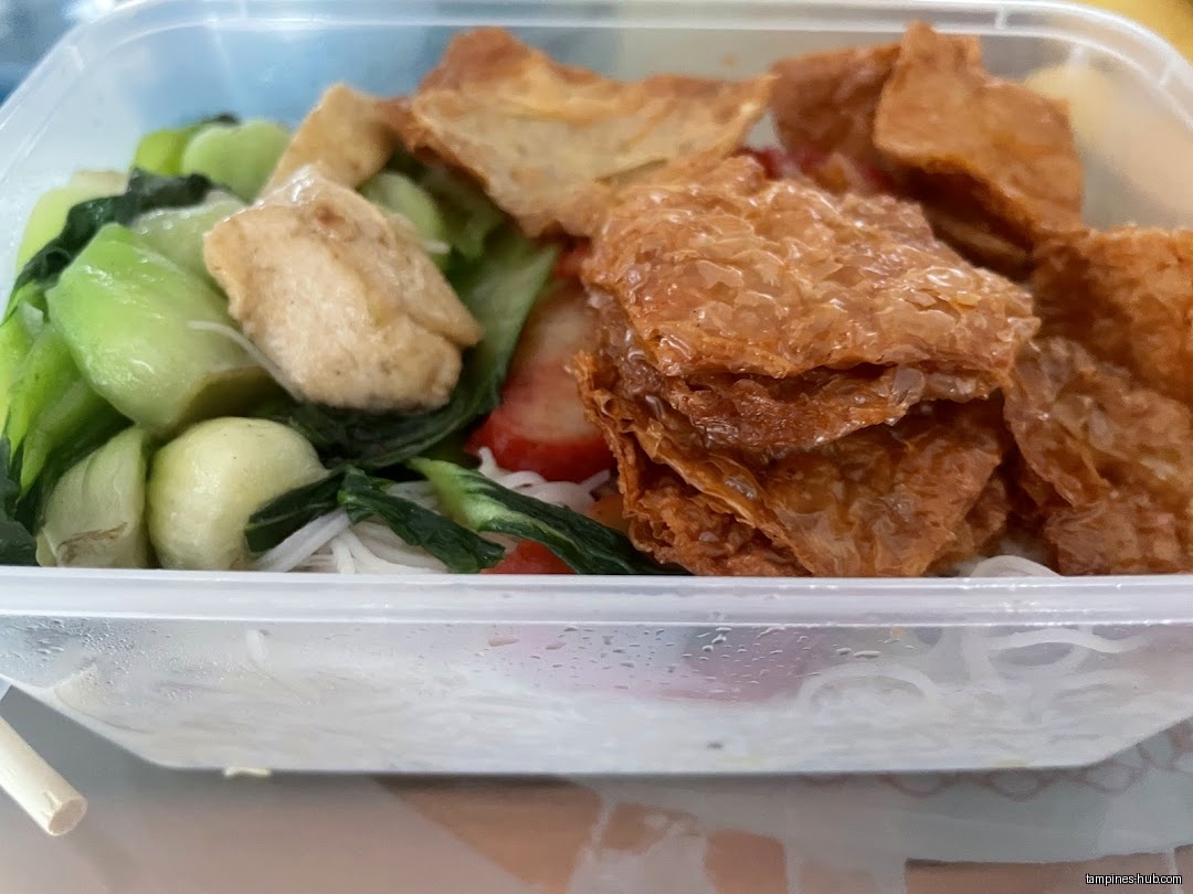 A plastic container holds a vegetarian meal with greens and fried tofu.