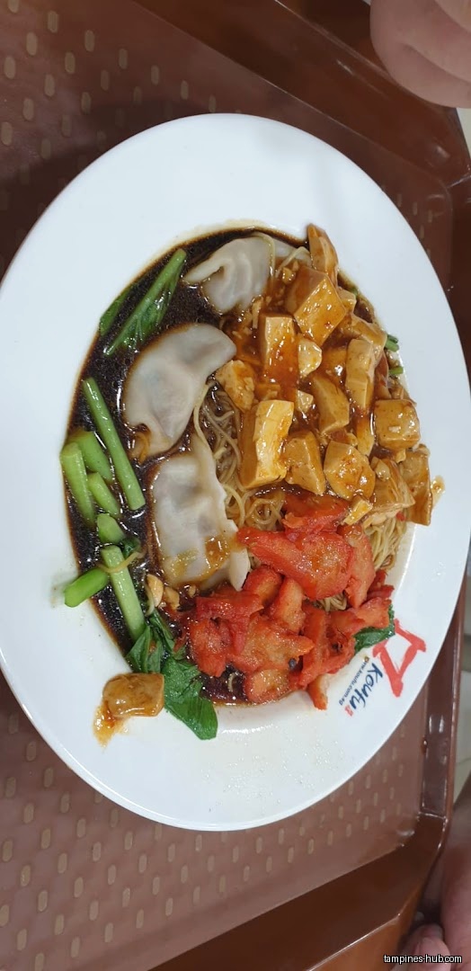 A plate of noodles with dumplings, tofu, and red char siew-like topping.